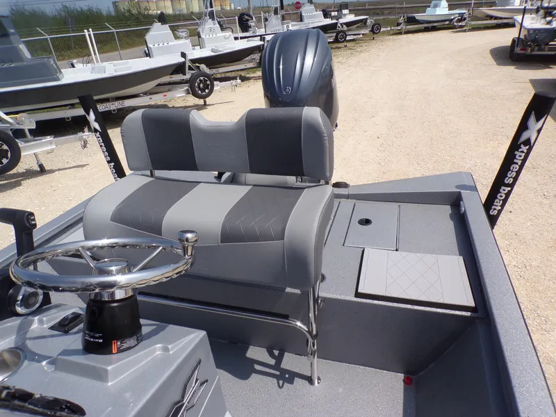 Slide: The Image of 2025 Xpress H210BAY boat interior with steering wheel and seating, displayed outdoors. - 22