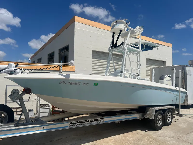 Slide: The Image of 2007 Young Boats Young 24 on trailer, parked outside a building under a clear blue sky. - 1