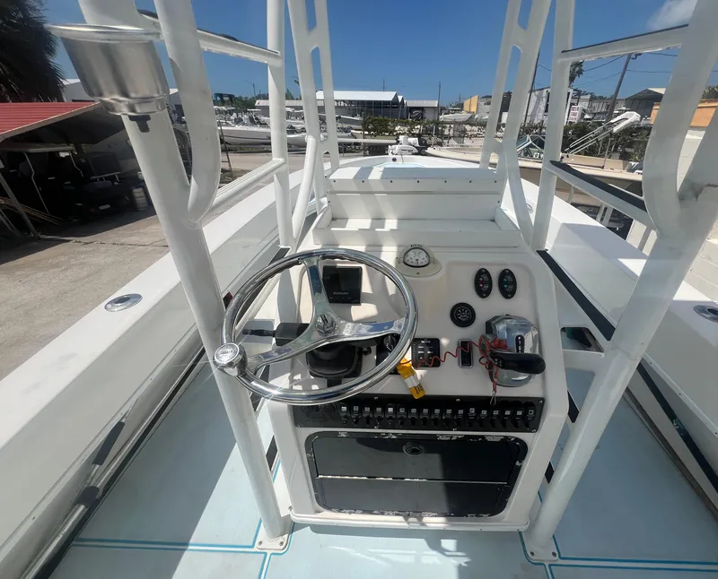 Slide: The Image of 2007 Young Boats Young 24 helm with steering wheel and controls, docked under clear skies. - 18