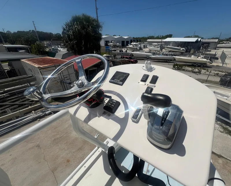 Slide: The Image of 2007 Young Boats Young 24 helm with steering wheel and controls, docked under clear sky. - 23
