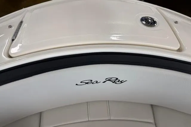 Slide: The Image of 2025 Sea Ray SPX 210 boat interior with logo, featuring sleek white seating and storage compartment. - 9