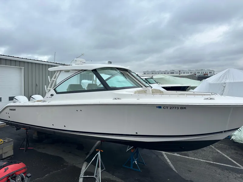 Slide: The Image of 2019 Pursuit DC 325 boat on a trailer in a marina setting. - 1