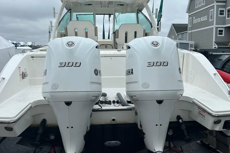 Slide: The Image of 2019 Pursuit DC 325 boat with twin Yamaha 300 engines, docked near coastal homes. - 18