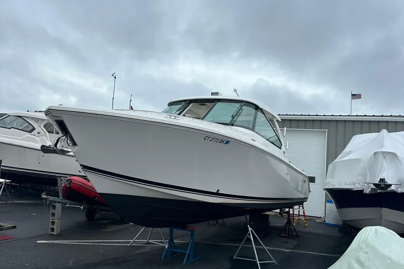 Slide: The Image of 2019 Pursuit DC 325 boat on stands, overcast sky, marina setting. - 2