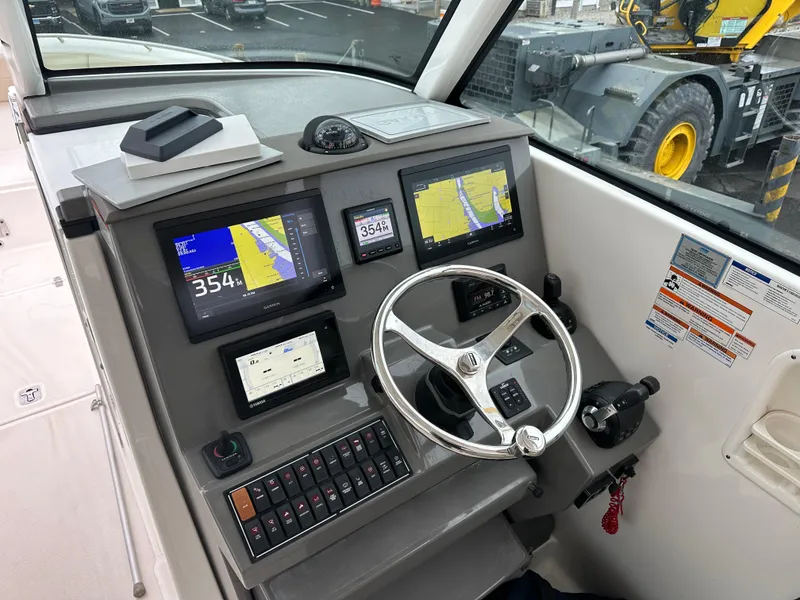 Slide: The Image of Control panel of a 2019 Pursuit DC 325 boat with navigation screens and steering wheel. - 3
