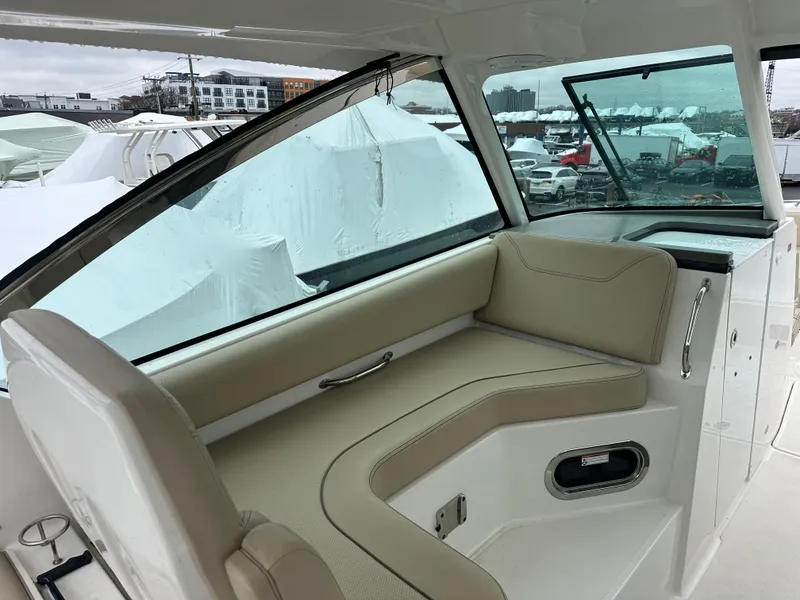 Slide: The Image of 2019 Pursuit DC 325 boat interior with beige seating and large windows. - 5