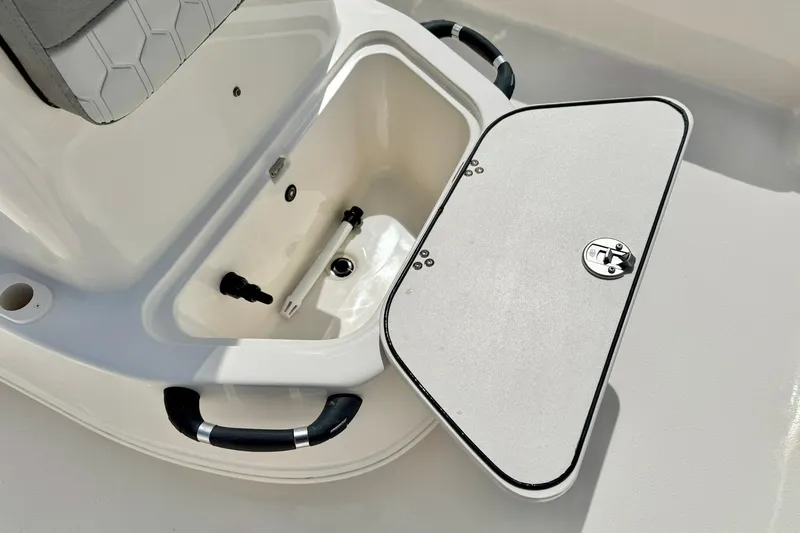 Slide: The Image of 2025 Carolina Skiff 21 LS boat storage compartment with open lid and handles. - 16