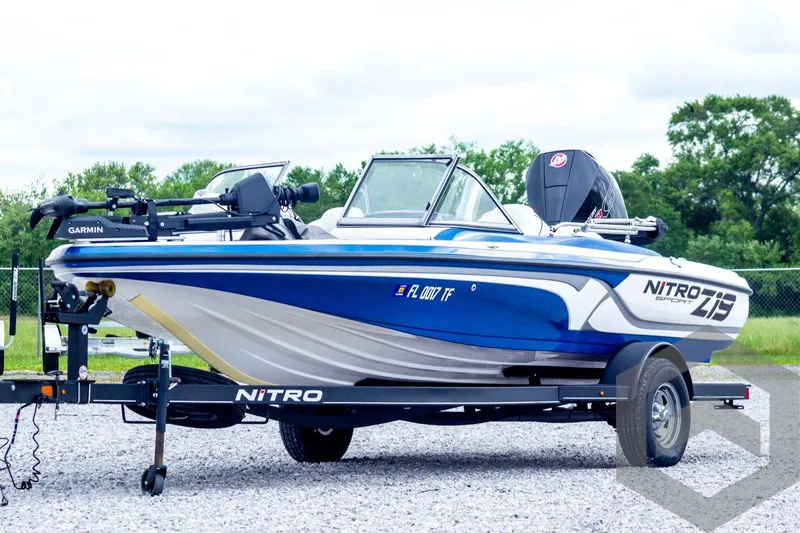 Slide: The Image of 2022 Nitro Z19 Sport boat on trailer, blue and white design, parked outdoors. - 1