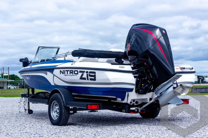 Slide: The Image of 2022 Nitro Z19 Sport boat with outboard motor on a trailer, parked on gravel. - 15