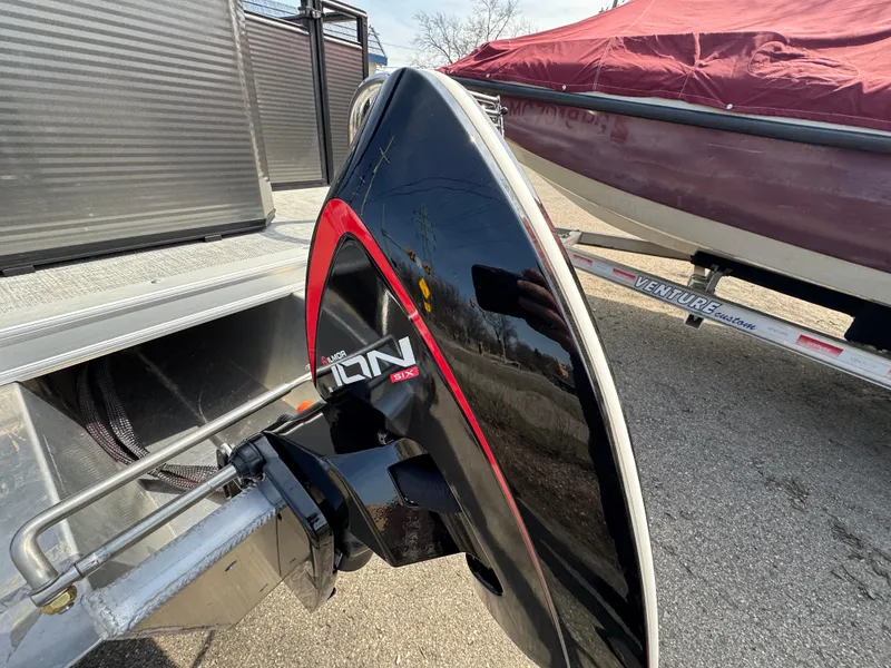 Slide: The Image of 2025 Qwest E 20 Lanai boat with sleek black and red design on a trailer. - 6