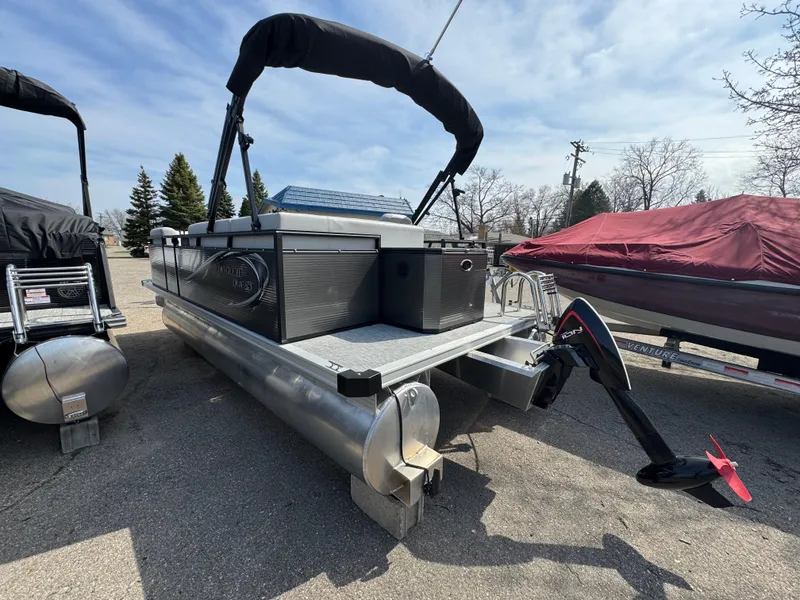 Slide: The Image of 2025 Qwest E 20 Lanai pontoon boat with outboard motor, parked outdoors. - 8