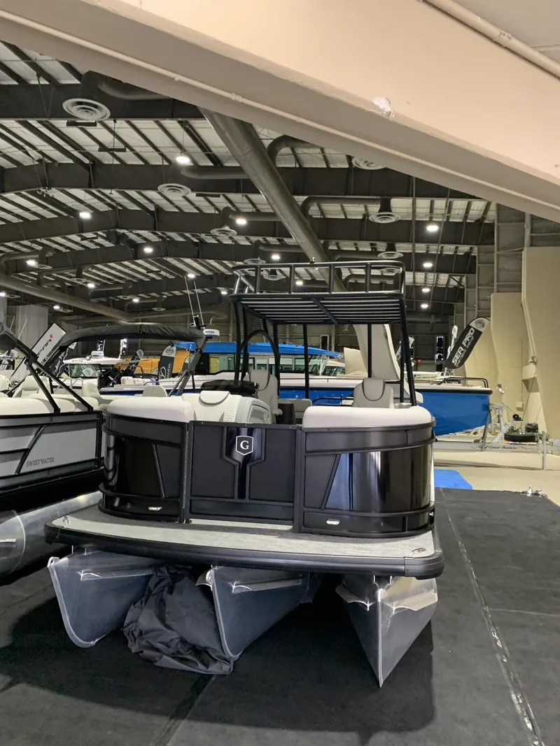 Slide: The Image of 2025 Godfrey Monaco 235 SD pontoon boat displayed indoors at a boat show. - 1