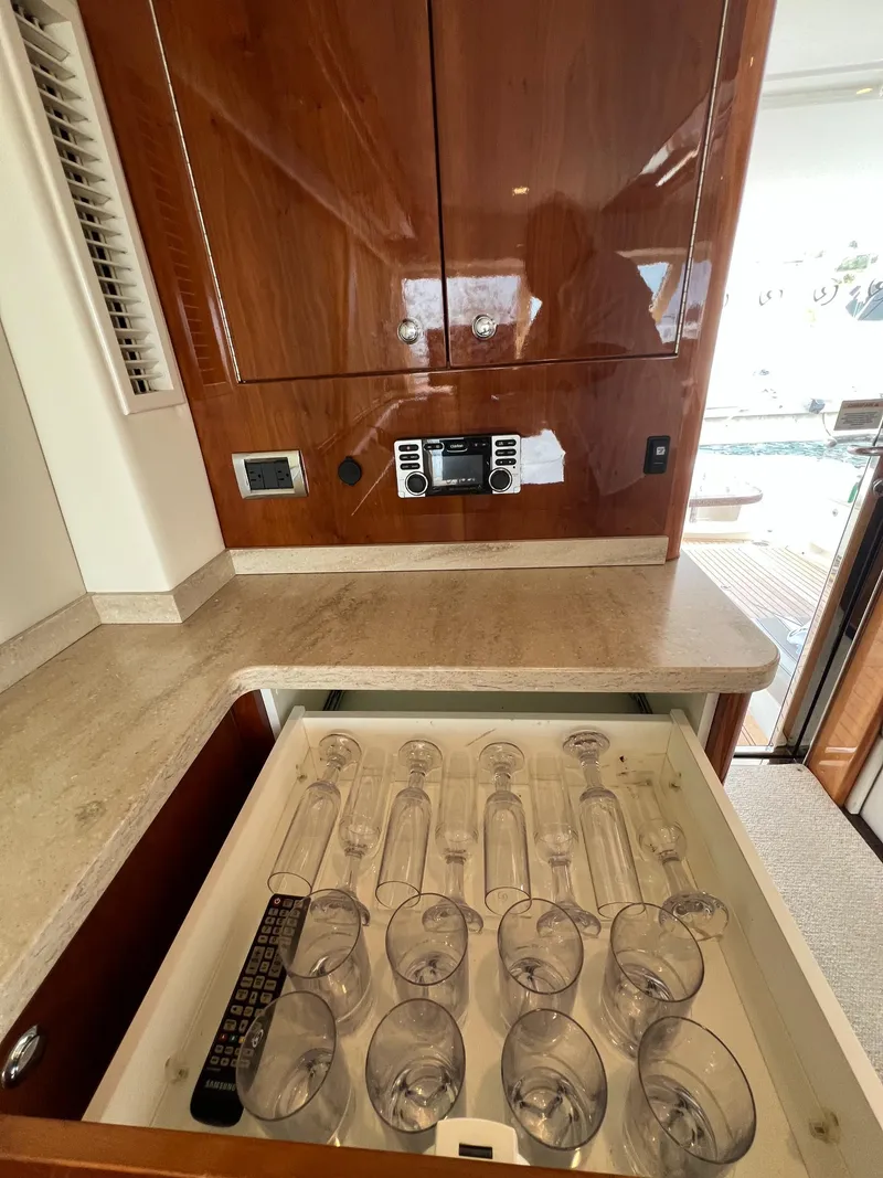 Slide: The Image of Luxurious 2016 Riviera 45 Open Flybridge interior with glassware drawer and wooden cabinetry. - 11