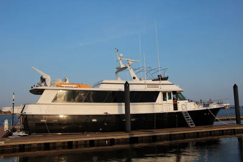 The Image of 1985 Hatteras 72 Motor Yacht docked at marina under clear blue sky. - 0