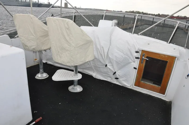 Slide: The Image of 1985 Hatteras 72 Motor Yacht deck with covered seats and door, overlooking water. - 11