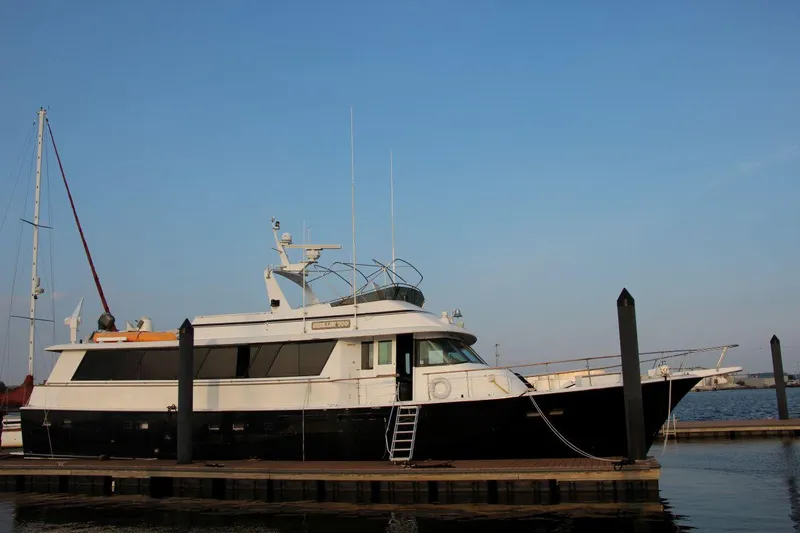 Slide: The Image of 1985 Hatteras 72 Motor Yacht docked at marina under clear blue sky. - 2