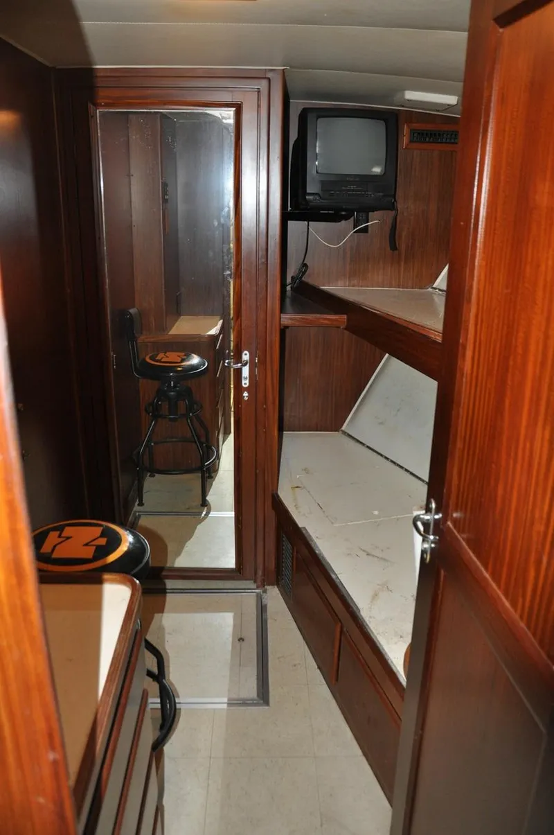 Slide: The Image of 1985 Hatteras 72 Motor Yacht interior with wood paneling, bunk beds, and a small TV. - 21