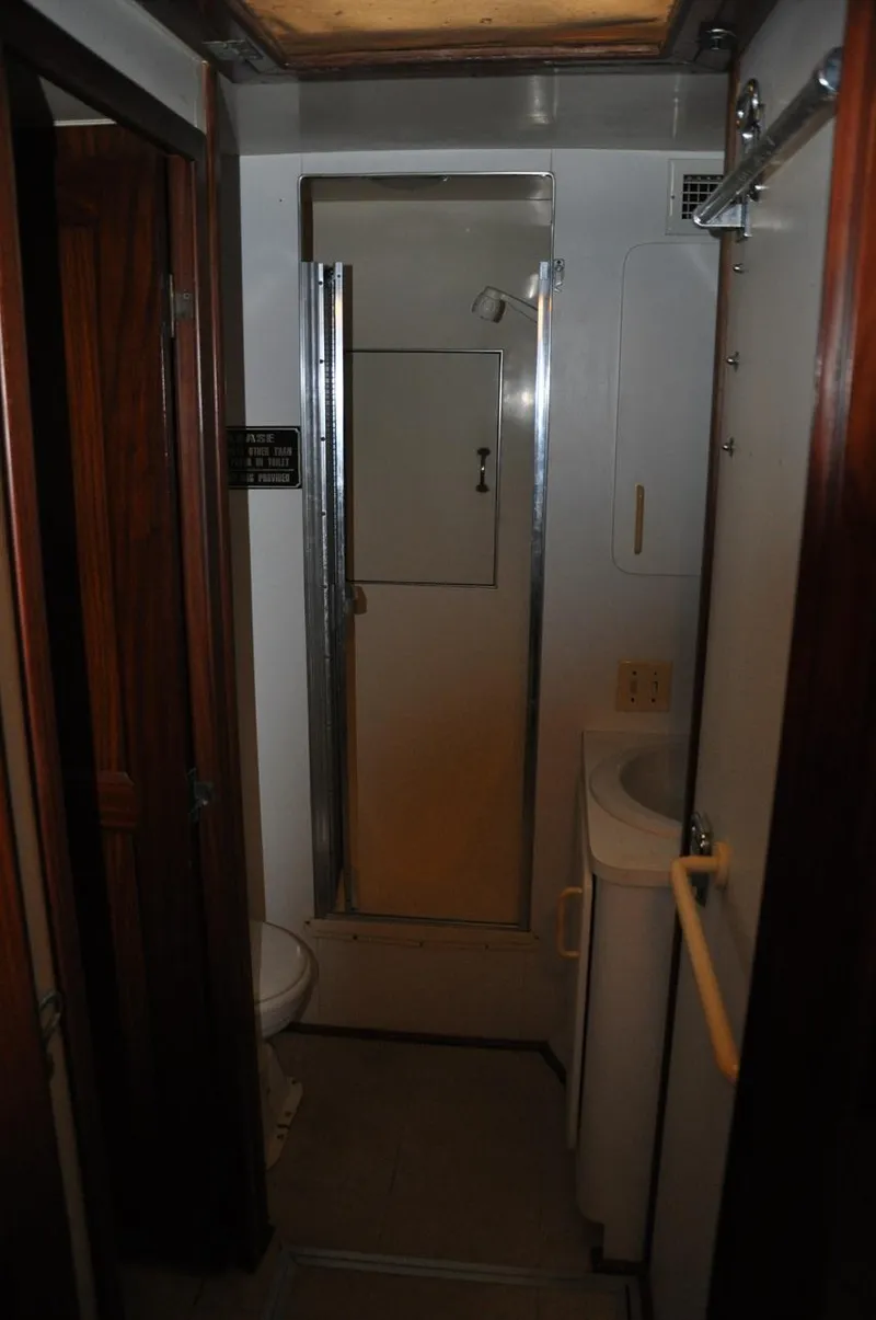 Slide: The Image of 1985 Hatteras 72 Motor Yacht bathroom with shower, sink, and wooden accents. - 23
