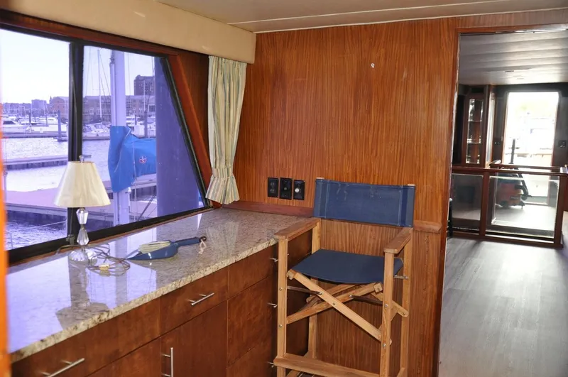 Slide: The Image of 1985 Hatteras 72 Motor Yacht interior with wood paneling, granite counter, and marina view. - 24