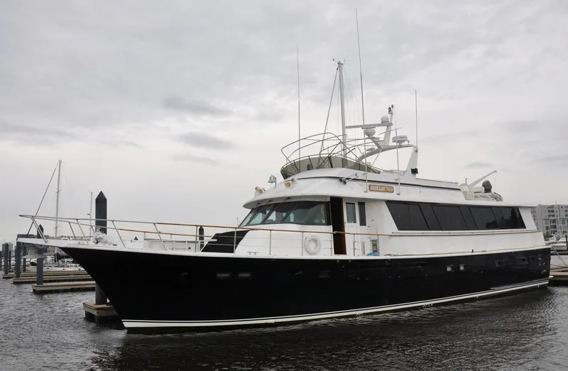 Slide: The Image of 1985 Hatteras 72 Motor Yacht docked in a marina under cloudy skies. - 3