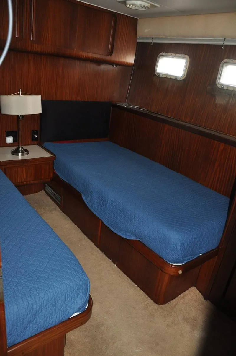Slide: The Image of 1985 Hatteras 72 Motor Yacht cabin with twin beds and wooden interior. - 34