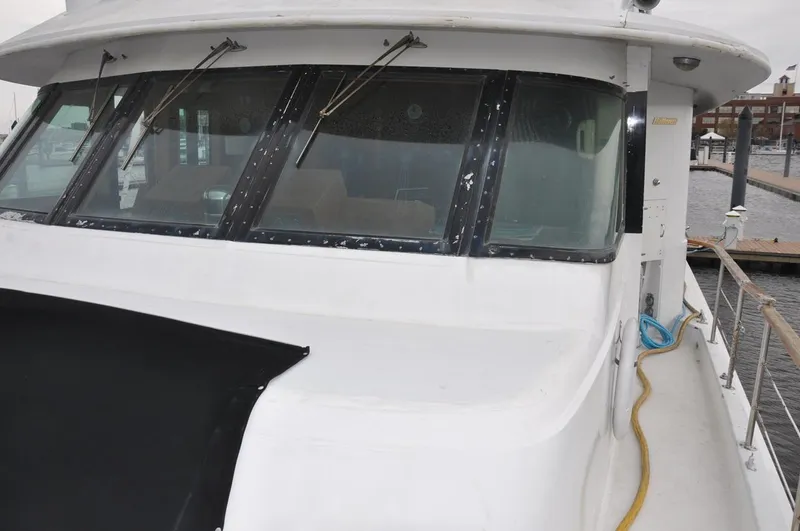 Slide: The Image of 1985 Hatteras 72 Motor Yacht docked, showcasing front windows and deck details. - 9