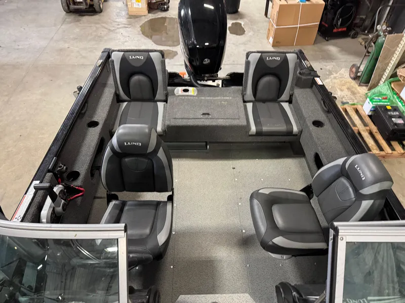 Slide: The Image of 2019 Lund 1675 Adventure Sport boat interior with four seats and motor, in a garage setting. - 3