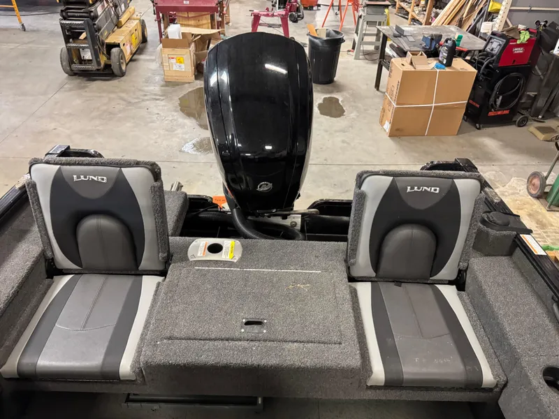 Slide: The Image of 2019 Lund 1675 Adventure Sport boat interior with dual seats and motor in a workshop. - 8