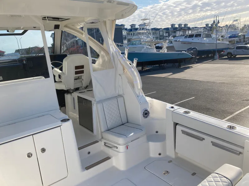 Slide: The Image of 2025 Pursuit OS 325 boat interior with seating and storage, docked at a marina. - 11