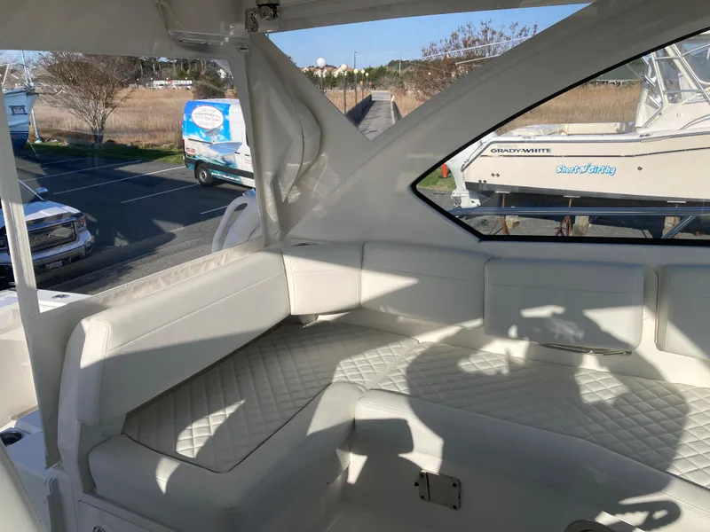 Slide: The Image of 2025 Pursuit OS 325 boat interior with white cushioned seating and window view. - 23