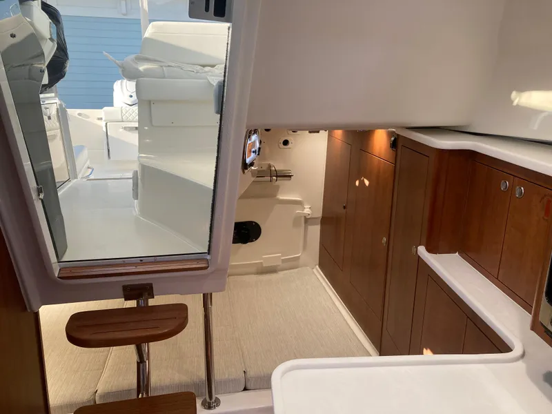 Slide: The Image of Interior view of 2025 Pursuit OS 325 boat, featuring wooden cabinetry and seating. - 25