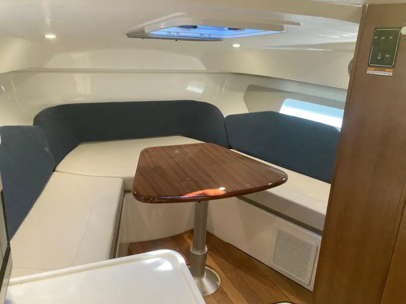 Slide: The Image of 2025 Pursuit OS 325 cabin interior with cozy seating and wooden table. - 27