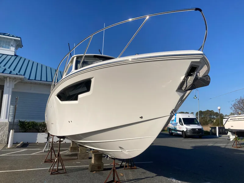 Slide: The Image of 2025 Pursuit OS 325 boat on stands, displayed outdoors under clear blue sky. - 3
