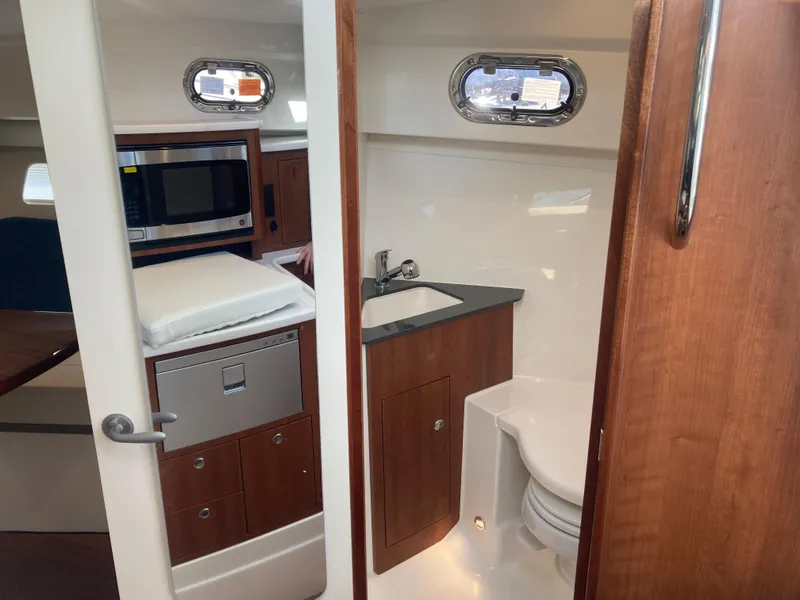 Slide: The Image of 2025 Pursuit OS 325 boat interior with kitchenette and compact bathroom. - 31