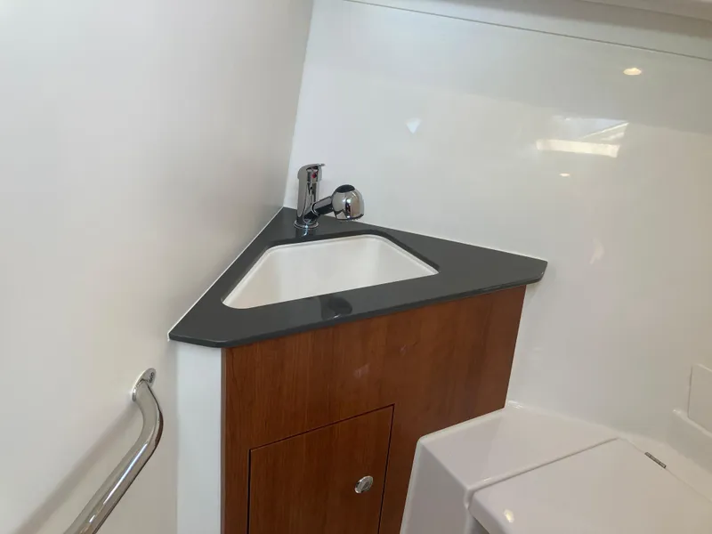 Slide: The Image of 2025 Pursuit OS 325 boat bathroom with modern sink and wooden cabinetry. - 32