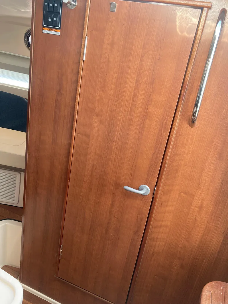 Slide: The Image of Wooden cabin door inside 2025 Pursuit OS 325 boat, featuring sleek handle and control panel. - 34
