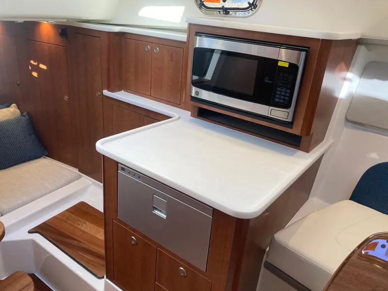 Slide: The Image of 2025 Pursuit OS 325 yacht interior with microwave and wooden cabinetry. - 35