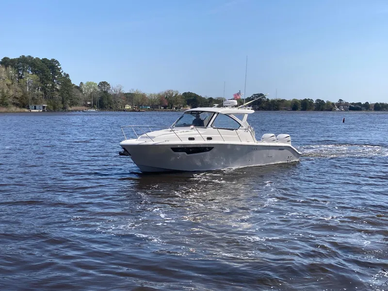 Slide: The Image of 2025 Pursuit OS 325 boat cruising on a calm lake under a clear blue sky. - 45