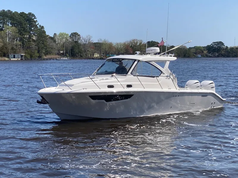 Slide: The Image of 2025 Pursuit OS 325 boat cruising on a calm river with trees in the background. - 46