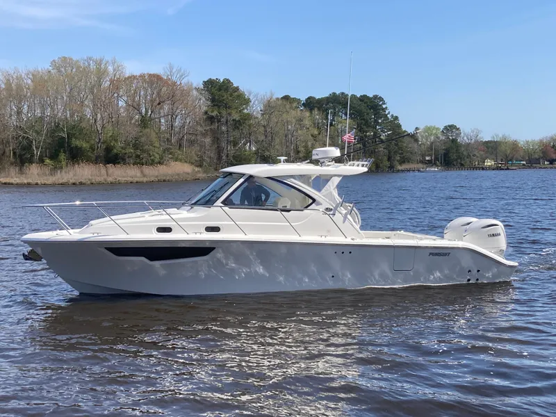 Slide: The Image of 2025 Pursuit OS 325 boat cruising on a calm river with trees in the background. - 48