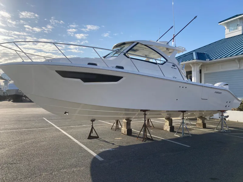Slide: The Image of 2025 Pursuit OS 325 boat on stands in a parking lot, clear sky background. - 5