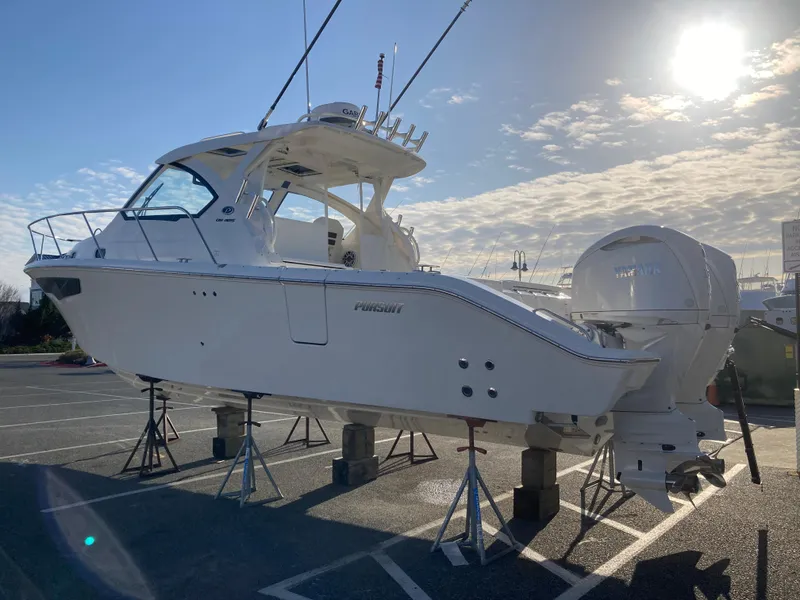 Slide: The Image of 2025 Pursuit OS 325 boat on stands in a sunny parking lot. - 6
