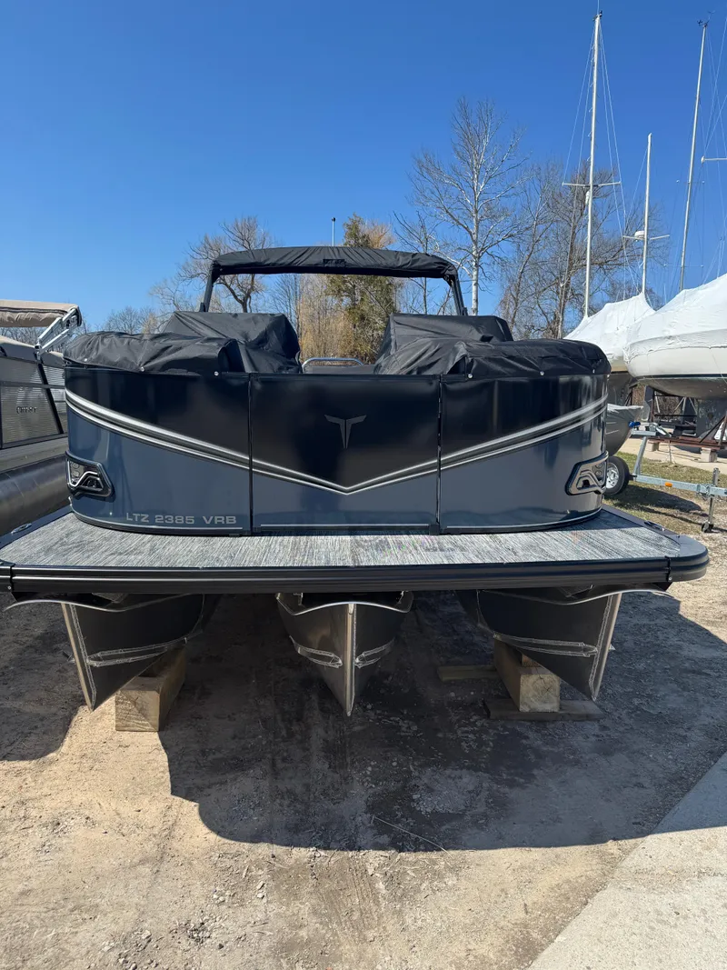 Slide: The Image of 2025 Tahoe Pontoon LTZ Versatile Rear Bench Windshield, docked outdoors under clear blue sky. - 1