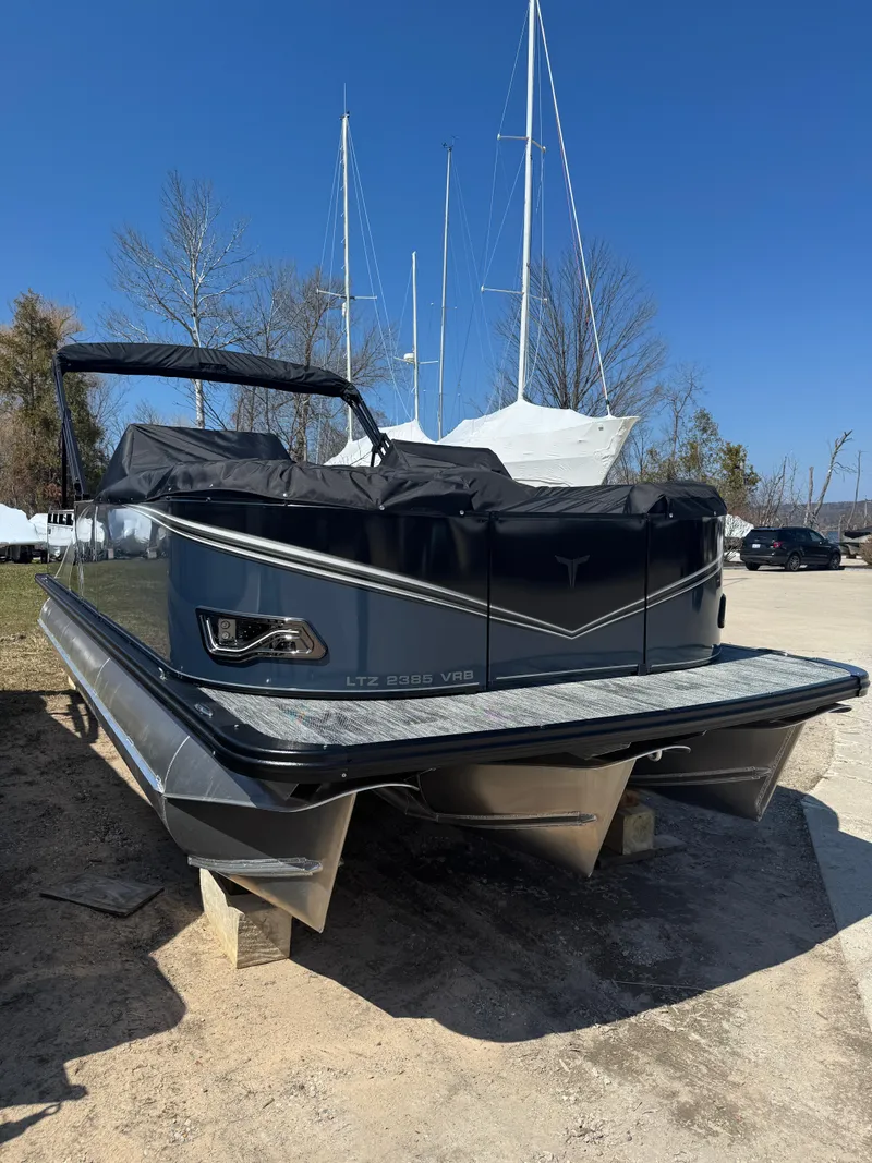Slide: The Image of 2025 Tahoe Pontoon LTZ Versatile Rear Bench Windshield, docked with sailboats in the background. - 2
