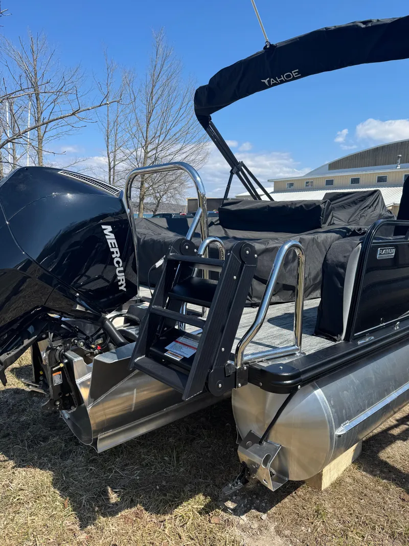 Slide: The Image of 2025 Tahoe Pontoon LTZ Versatile Rear Bench Windshield with Mercury engine, parked outdoors. - 6
