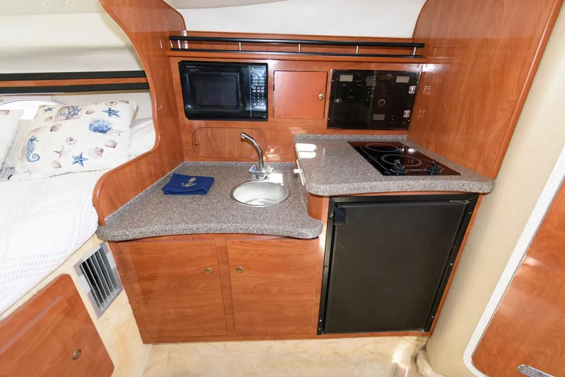 Slide: The Image of 2004 Rinker Fiesta Vee 312 cabin kitchen with sink, microwave, stove, and fridge. - 19