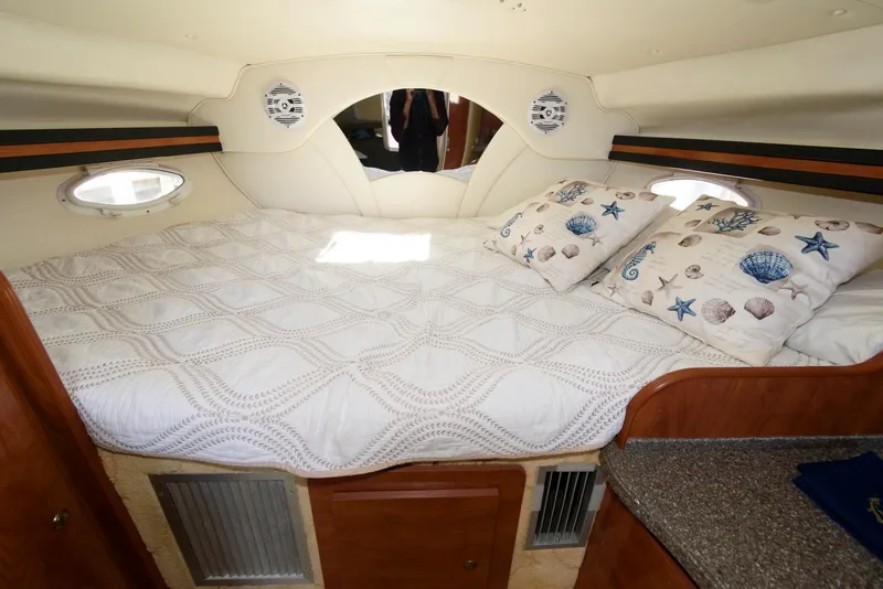 Slide: The Image of 2004 Rinker Fiesta Vee 312 cabin interior with cozy bed and nautical-themed pillows. - 20