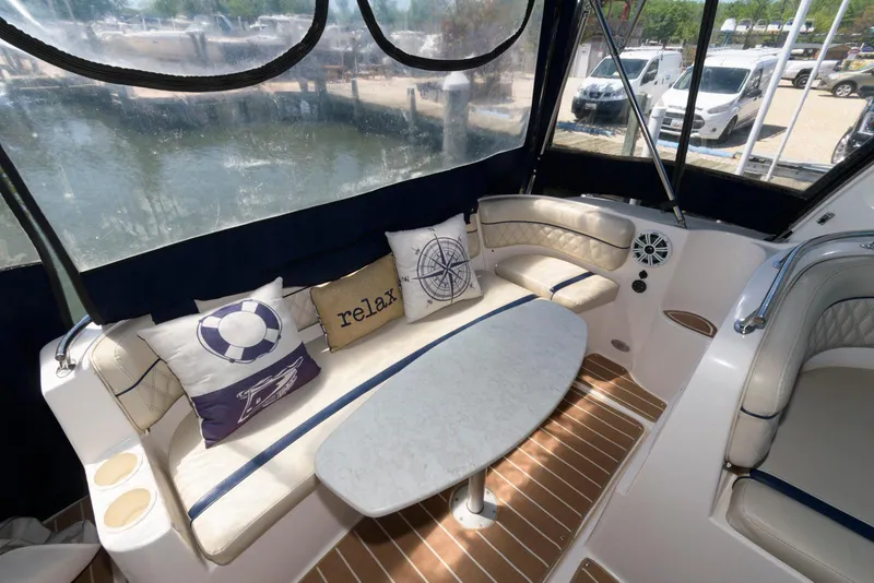 Slide: The Image of 2004 Rinker Fiesta Vee 312 interior with cushioned seating, nautical pillows, and oval table. - 6
