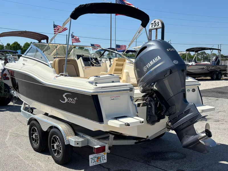 Slide: The Image of 2018 Scout 210 Dorado boat with Yamaha engine on trailer, flags in background. - 13