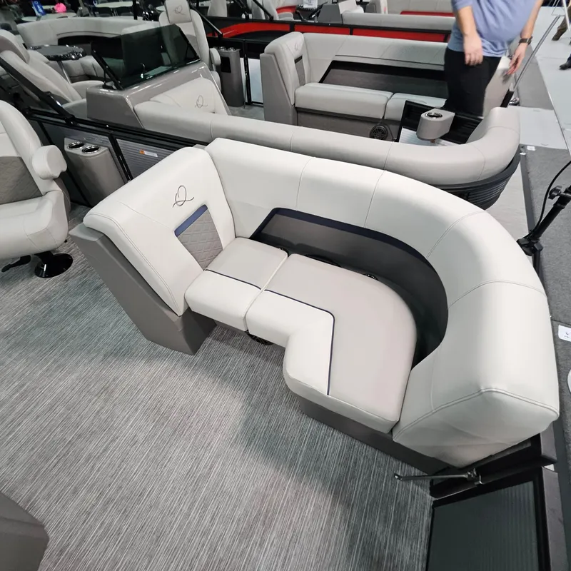 Slide: The Image of 2025 Qwest E 20RLS boat interior with modern, curved seating and gray upholstery. - 16